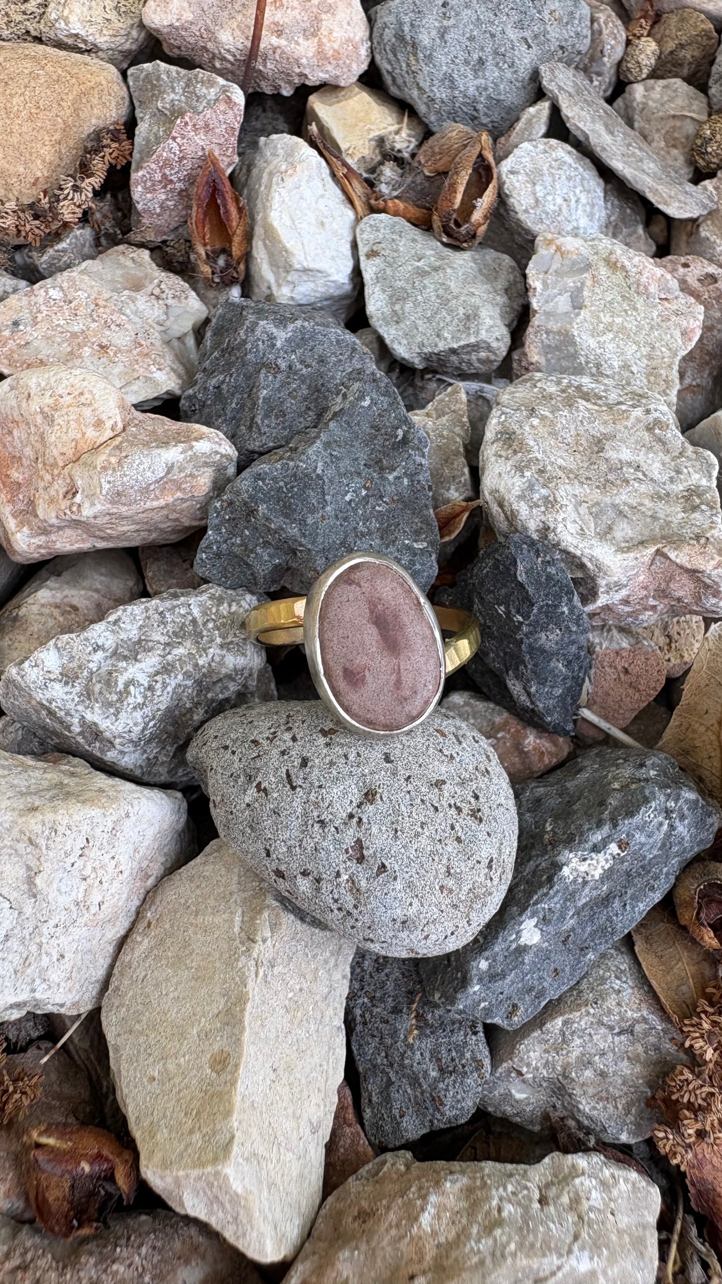 Gold ring with a pink stone on a bed of small rocks
