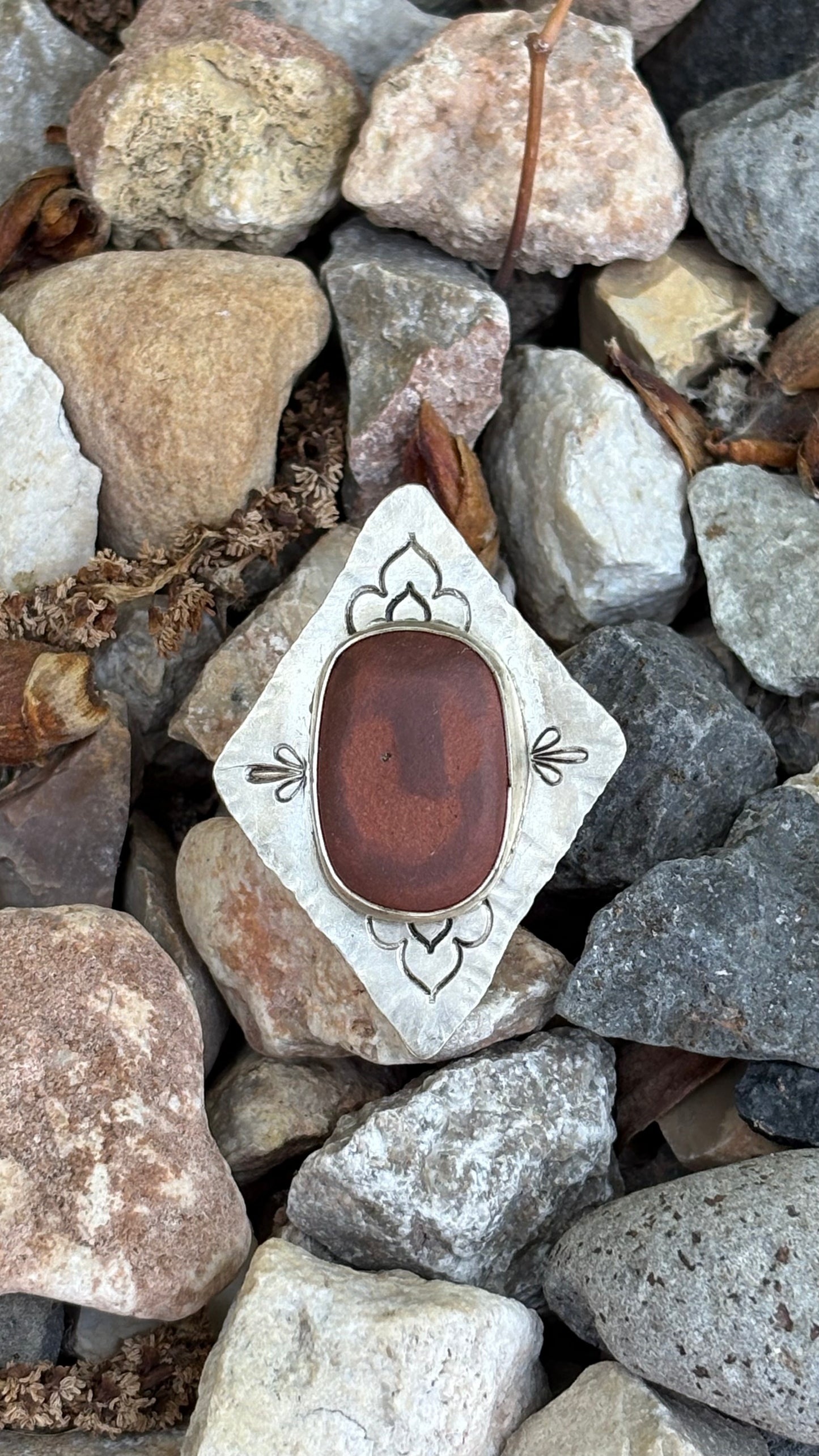 Decorative stone with a brown center and white border on a bed of rocks