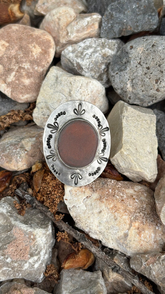Silver circular object with decorative edge on a bed of stones