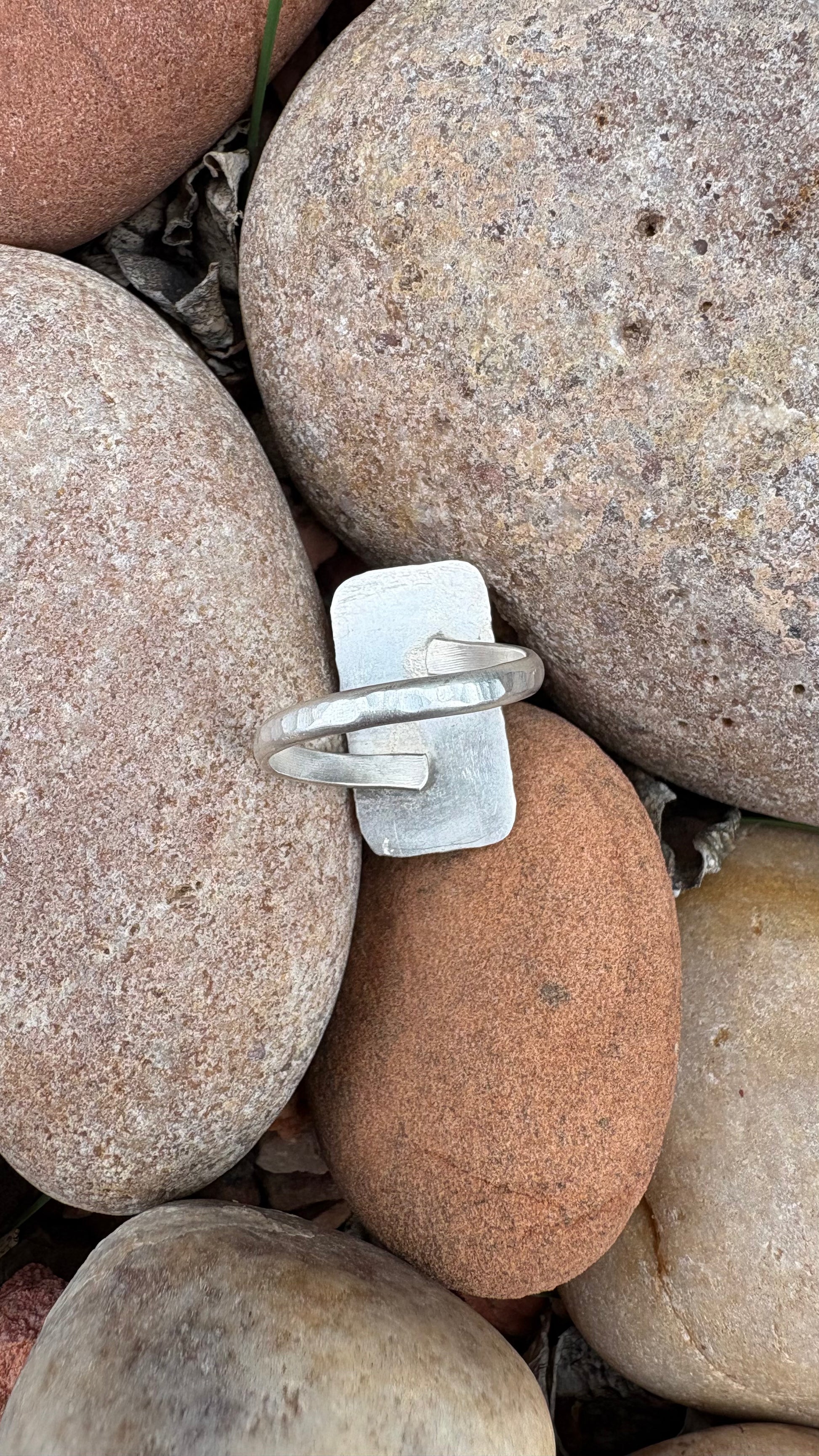 Silver ring on a bed of multicolored stones