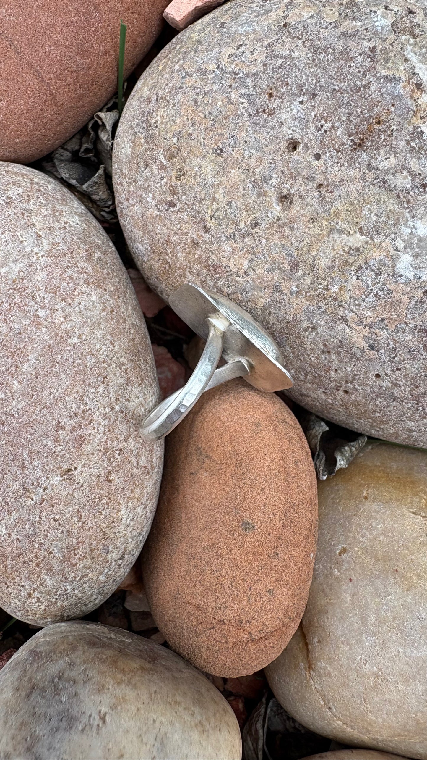 Close-up of a small metallic object embedded in pebbles